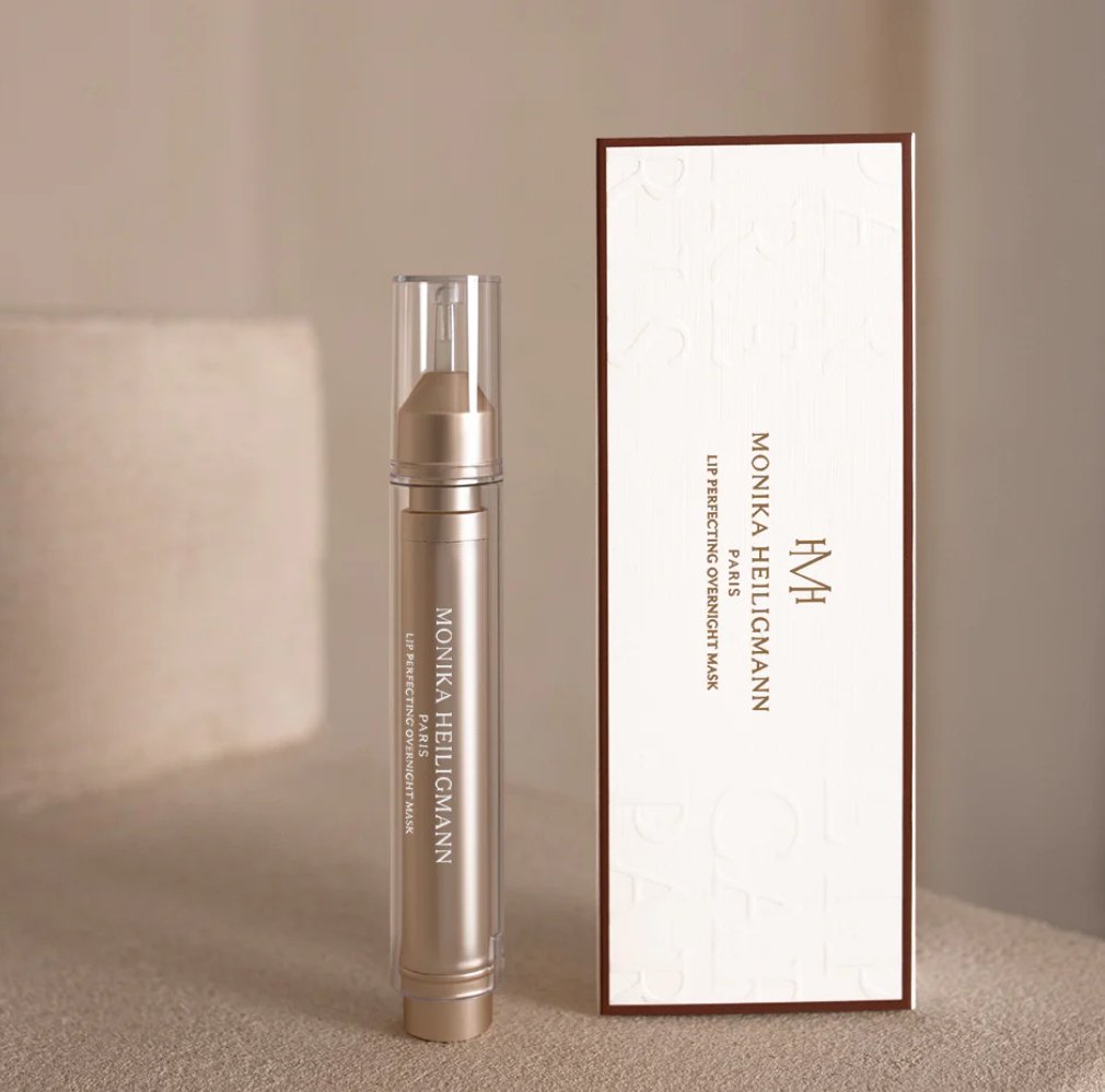 A lip perfecting overnight mask product in a clear tube with a white applicator, displayed in front of its packaging box
