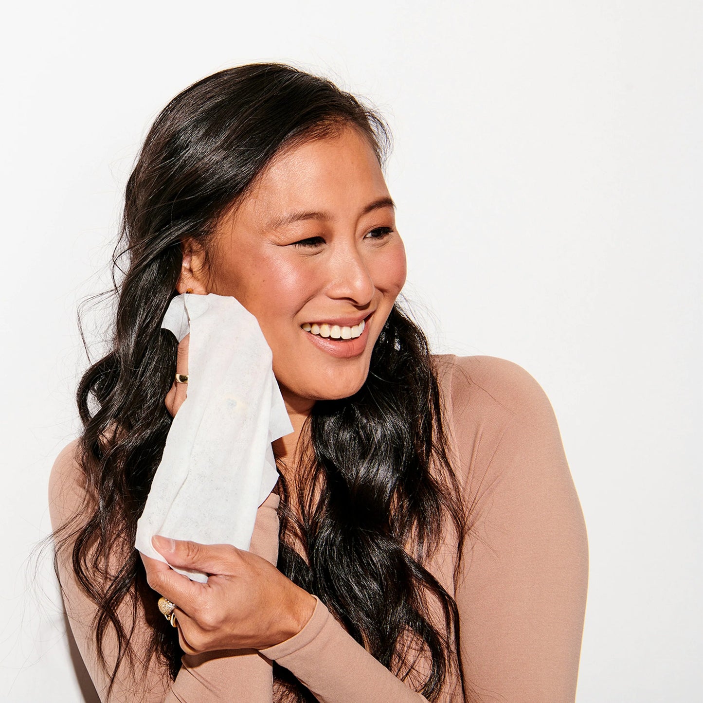 Woman holding a white tissue with a plain background